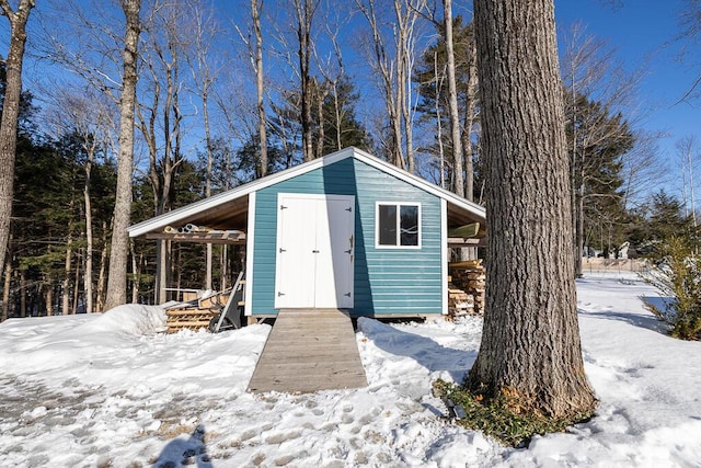 snow covered structure with an outdoor structure and a shed