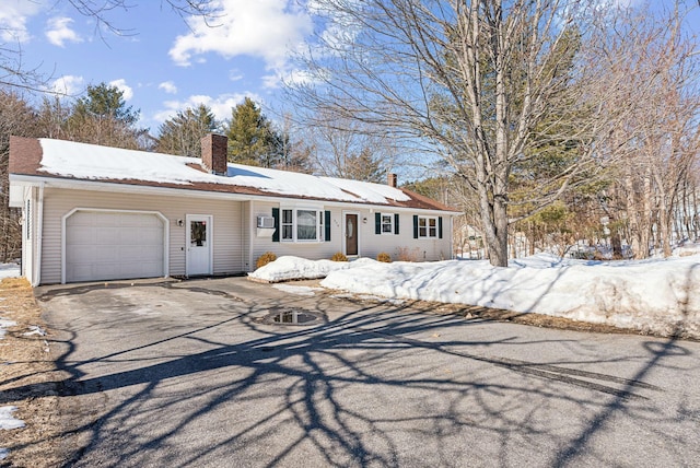 single story home with a garage, a chimney, and aphalt driveway