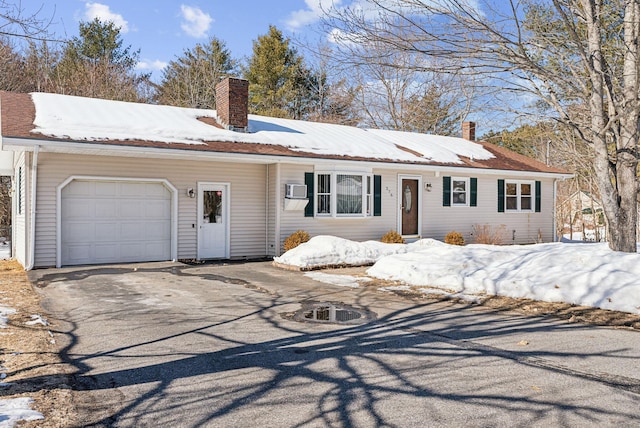 ranch-style house featuring aphalt driveway, a chimney, and an attached garage