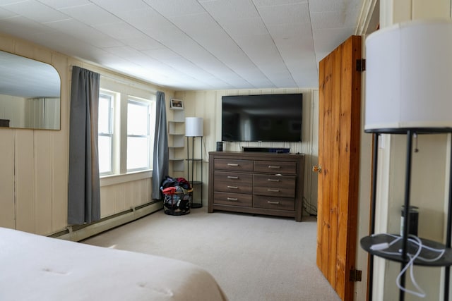 bedroom featuring light carpet, wooden walls, and baseboard heating