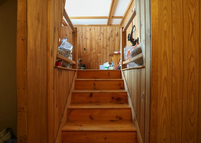 staircase featuring wood walls