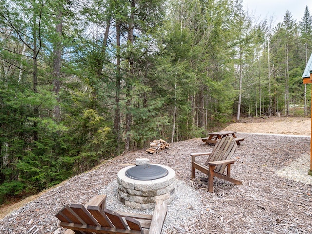 view of patio / terrace with an outdoor fire pit and a view of trees