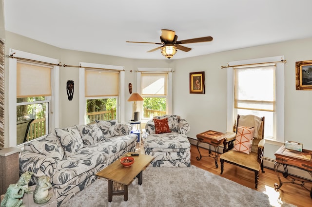 living area featuring a ceiling fan, a baseboard heating unit, and wood finished floors