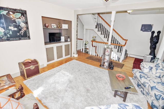 living room with a baseboard heating unit, stairway, and wood finished floors