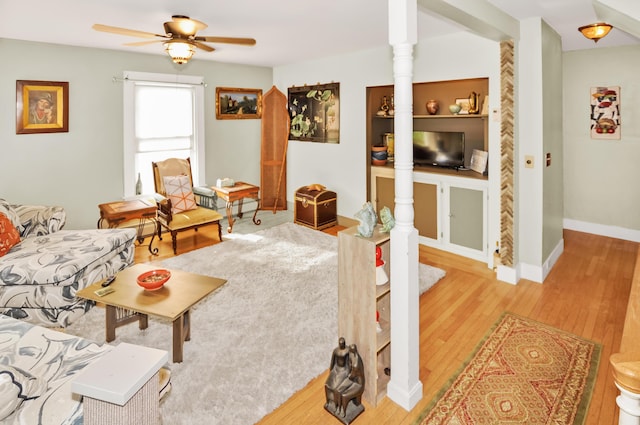 living room featuring light wood-style flooring, baseboards, and a ceiling fan