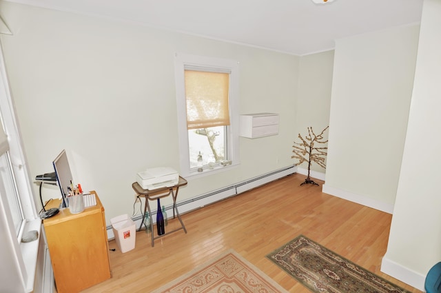 living area with ornamental molding, light wood finished floors, baseboard heating, and baseboards