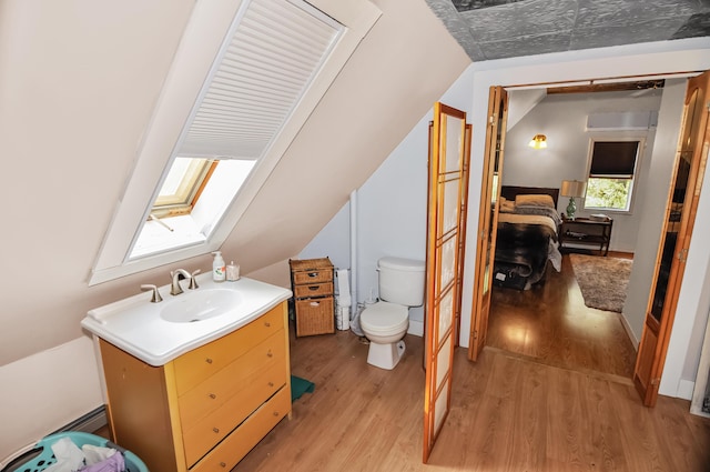 bathroom featuring lofted ceiling with skylight, vanity, toilet, and wood finished floors