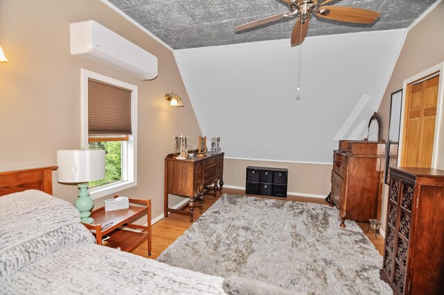 bedroom featuring a ceiling fan, baseboards, an AC wall unit, and wood finished floors