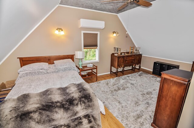 bedroom featuring lofted ceiling, baseboards, wood finished floors, and a wall mounted AC