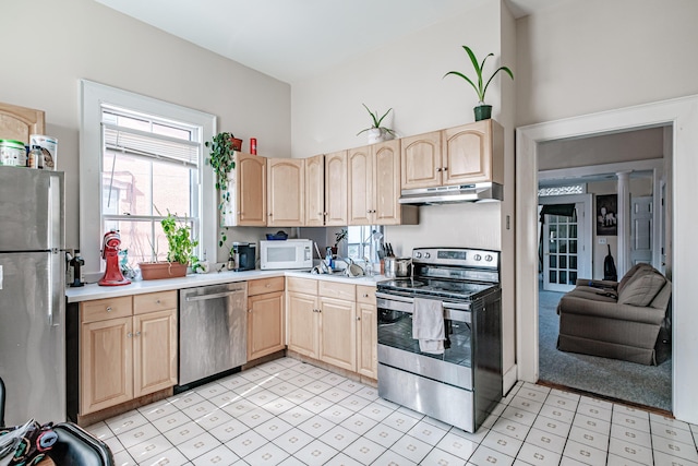 kitchen featuring light brown cabinets, under cabinet range hood, light floors, light countertops, and appliances with stainless steel finishes