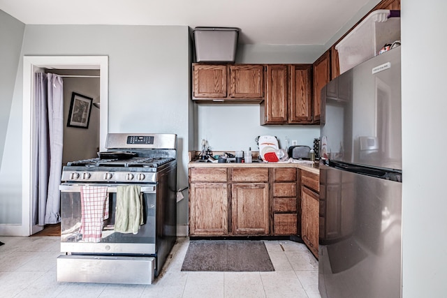 kitchen featuring light tile patterned floors, stainless steel appliances, brown cabinets, and light countertops