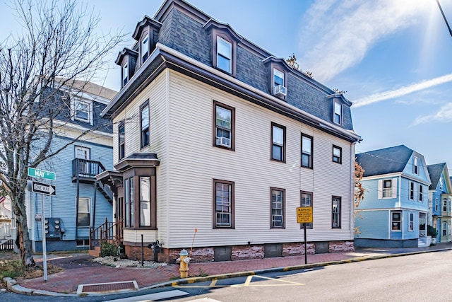 view of home's exterior featuring a residential view, cooling unit, mansard roof, and a shingled roof