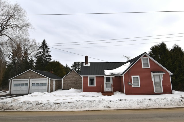 view of front facade featuring a garage, a chimney, and an outdoor structure