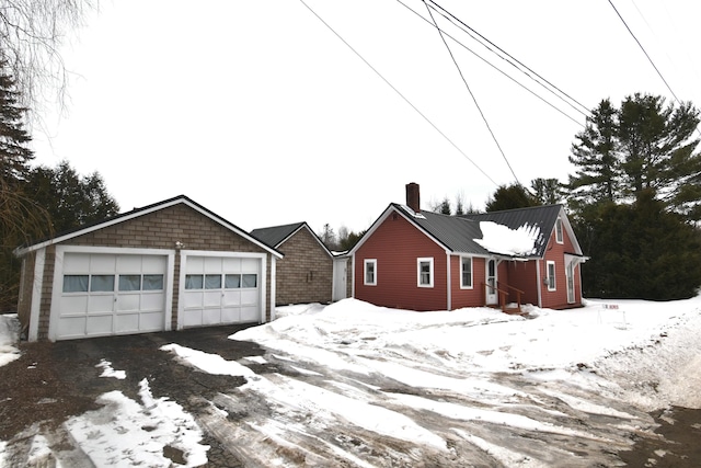 exterior space with a garage, metal roof, an outdoor structure, and a chimney