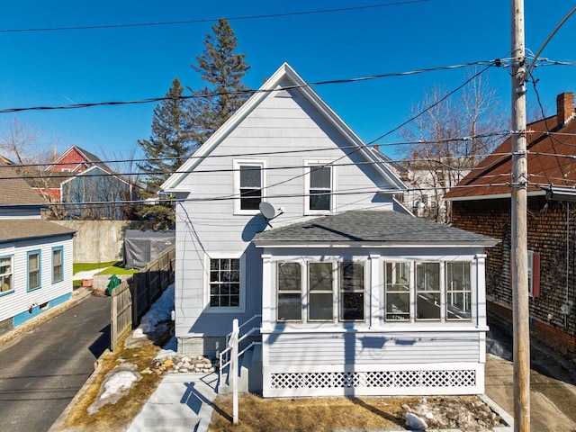 back of house featuring driveway and a shingled roof