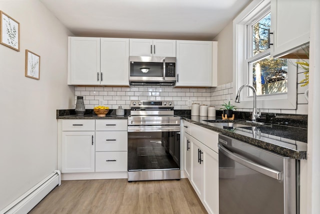 kitchen with tasteful backsplash, a baseboard radiator, stainless steel appliances, white cabinetry, and a sink