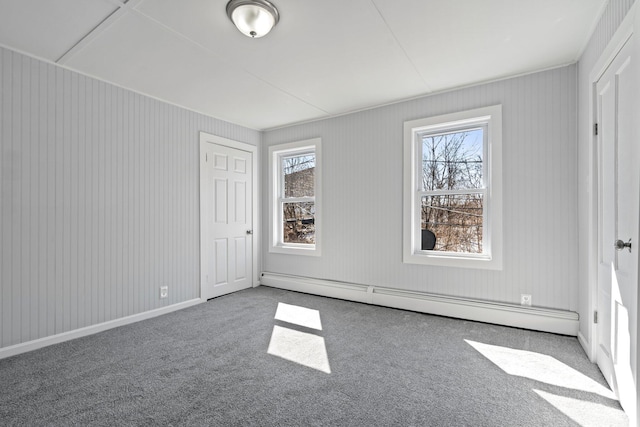 carpeted spare room with a baseboard radiator, plenty of natural light, and baseboards