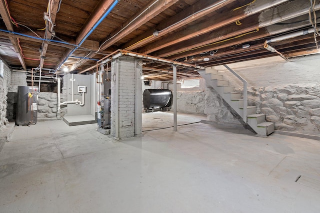 basement featuring water heater, stairway, and heating fuel