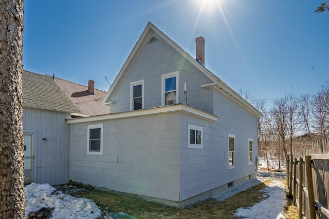 back of property featuring a chimney and fence