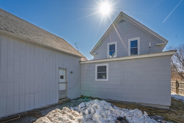 view of side of property featuring fence and roof with shingles