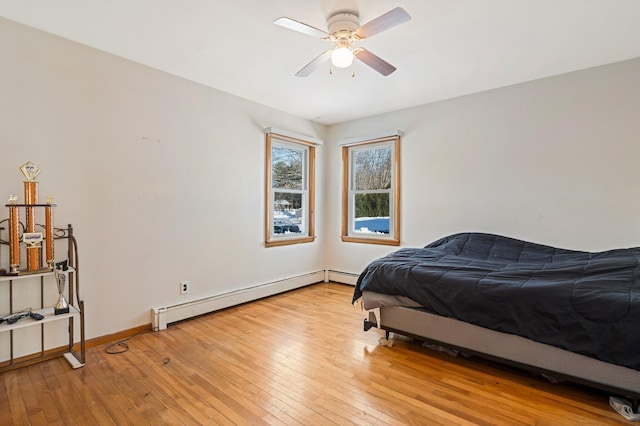 bedroom featuring a baseboard radiator, baseboards, ceiling fan, and light wood finished floors