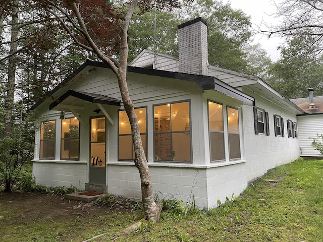 view of home's exterior with concrete block siding and a chimney