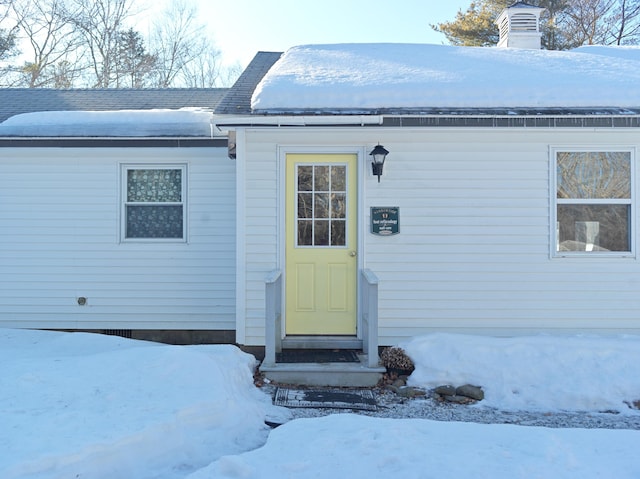 snow covered property entrance featuring a chimney