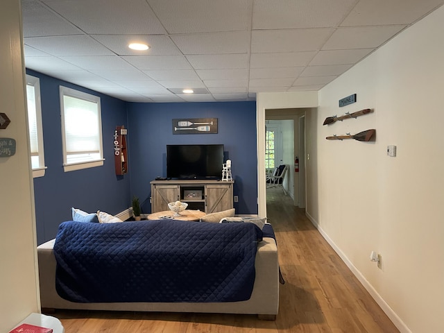 bedroom featuring wood finished floors, baseboards, and a drop ceiling