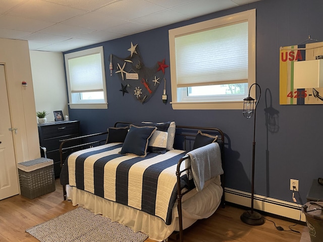 bedroom featuring multiple windows, wood finished floors, and baseboard heating