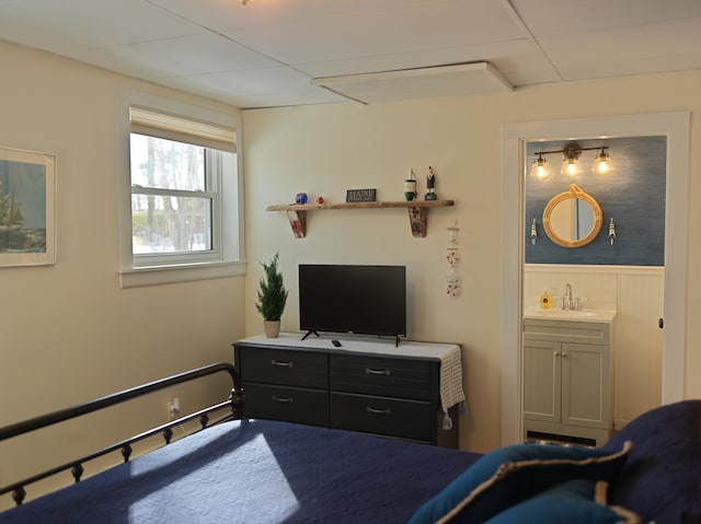 bedroom with a sink, a wainscoted wall, and ensuite bathroom