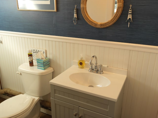 bathroom with a wainscoted wall, toilet, and vanity