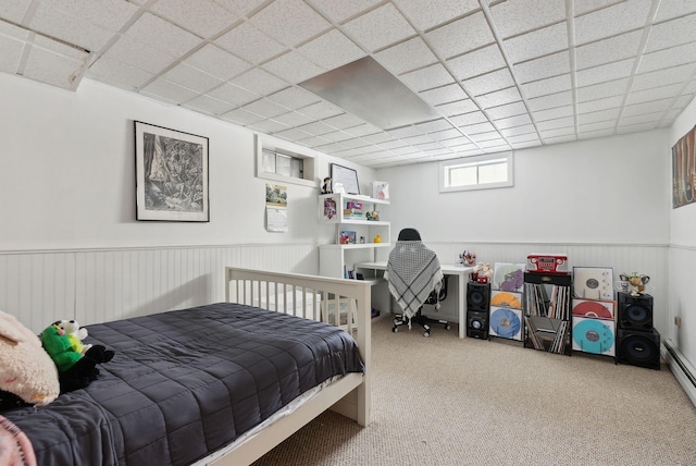 carpeted bedroom featuring a drop ceiling and wainscoting