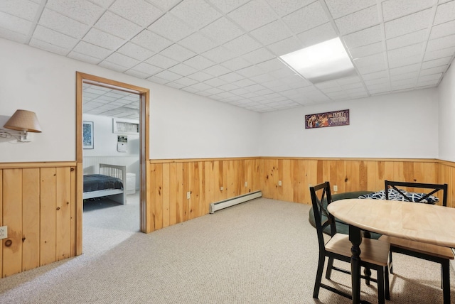 dining room with a wainscoted wall, baseboard heating, carpet flooring, and wooden walls