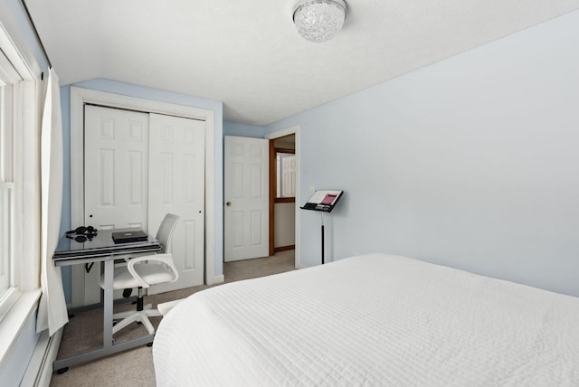 bedroom featuring light carpet, a closet, and lofted ceiling