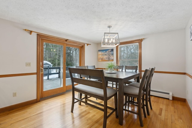 dining area with a baseboard radiator, baseboards, a textured ceiling, and light wood finished floors