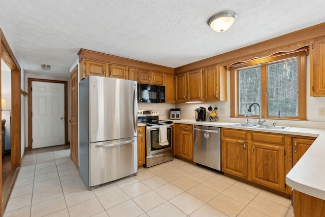 kitchen with light tile patterned floors, brown cabinetry, stainless steel appliances, light countertops, and a sink