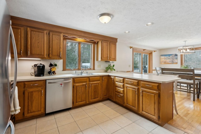 kitchen featuring a peninsula, brown cabinetry, and stainless steel appliances