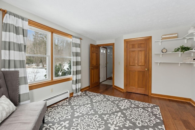 interior space with a baseboard radiator, a textured ceiling, baseboards, and wood finished floors