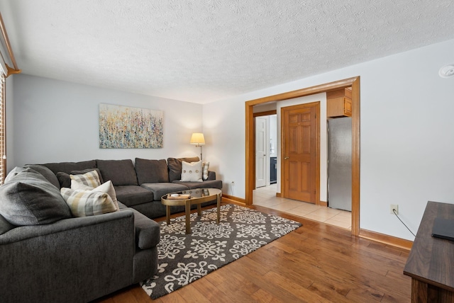 living room with light wood-style flooring, baseboards, and a textured ceiling