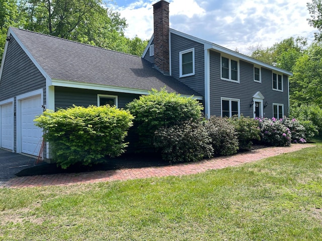 view of front of property featuring a garage, a shingled roof, a chimney, and a front yard