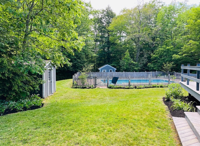 view of yard with a fenced in pool, an outbuilding, fence, and a storage shed