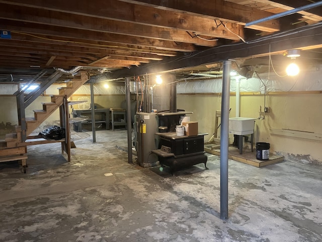 unfinished below grade area featuring electric water heater, a sink, and stairway