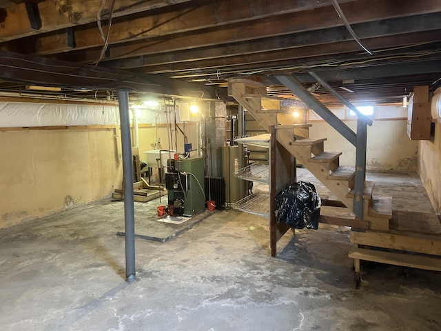 unfinished below grade area with water heater, a heating unit, and stairs