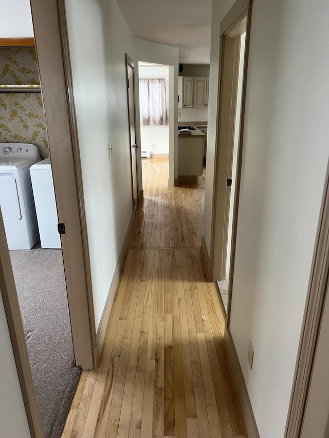 hall featuring washing machine and dryer, baseboards, light wood finished floors, and wallpapered walls