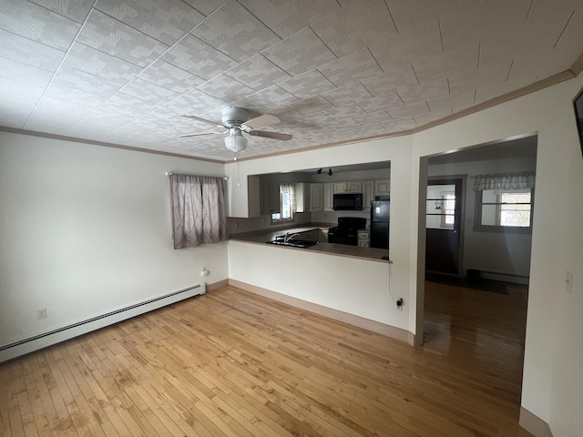 kitchen with black appliances, ornamental molding, baseboard heating, and wood-type flooring