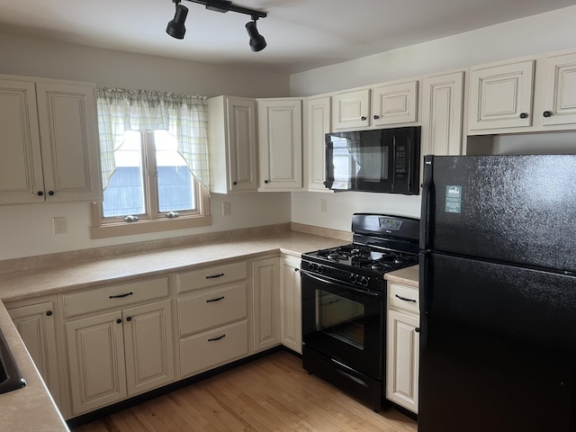 kitchen featuring white cabinets, light countertops, light wood-style flooring, and black appliances