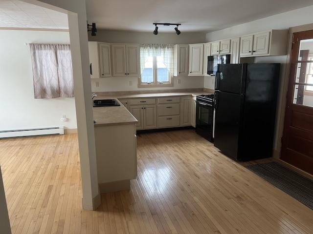 kitchen with light countertops, a sink, light wood finished floors, and black appliances