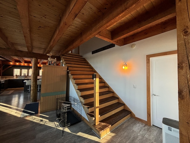 staircase featuring wooden ceiling, beam ceiling, baseboards, and wood finished floors