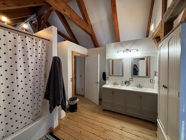 bathroom with double vanity, shower / tub combo, lofted ceiling with beams, hardwood / wood-style floors, and a sink