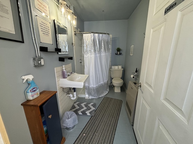 full bathroom with curtained shower, tile patterned flooring, a sink, and toilet